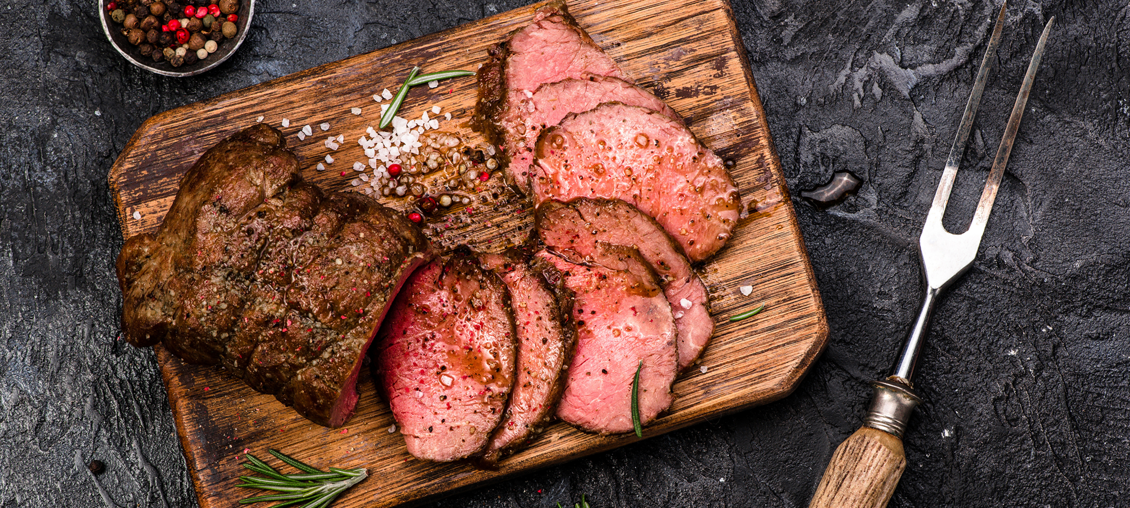 Faux-filet roulé dans du gros poivre et piqué de romarin. Cuit sur un lit d’oignons rouges